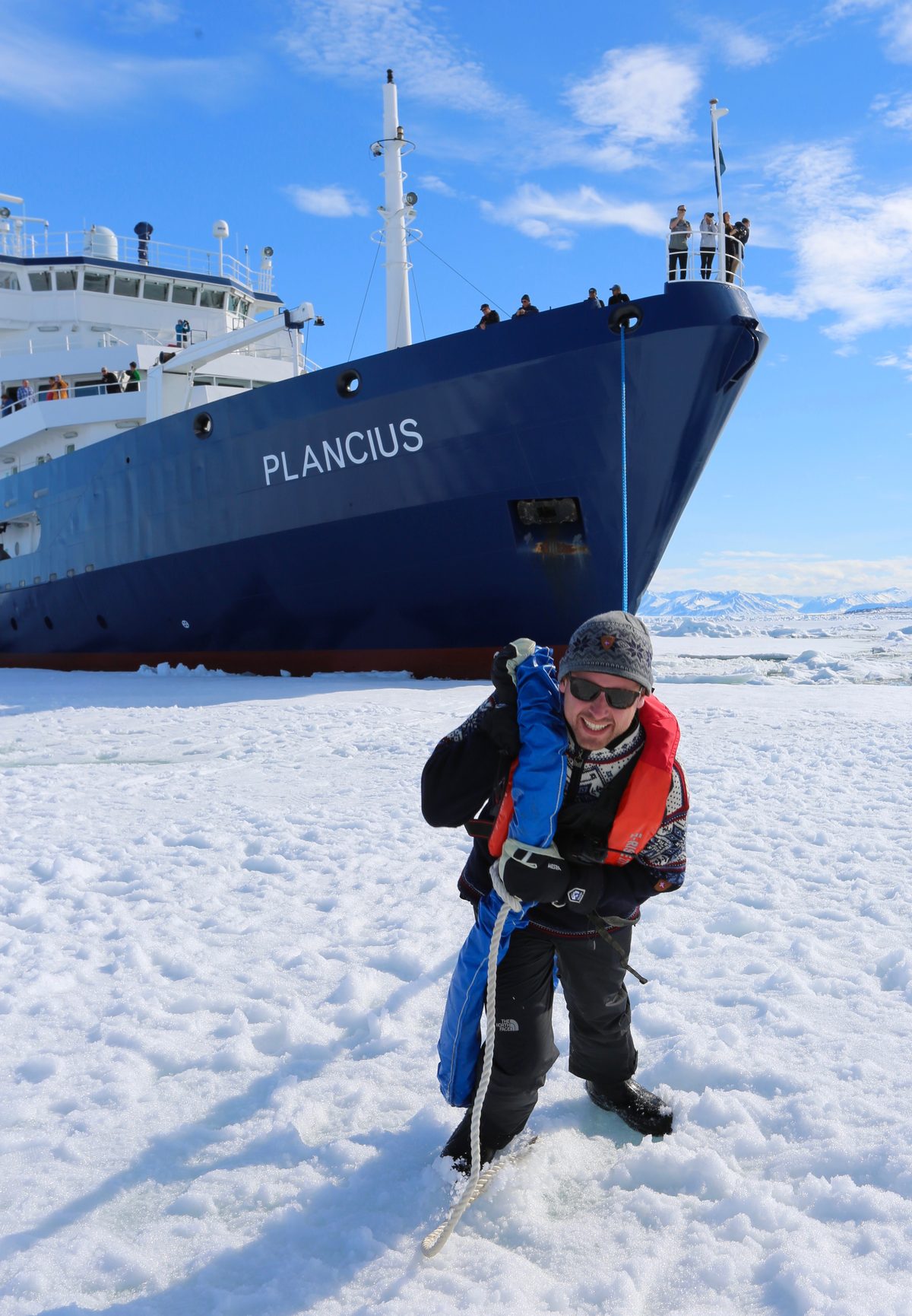 Bram Hulst hauling a mooring line across Arctic pack ice in front of the expedition ship Plancius